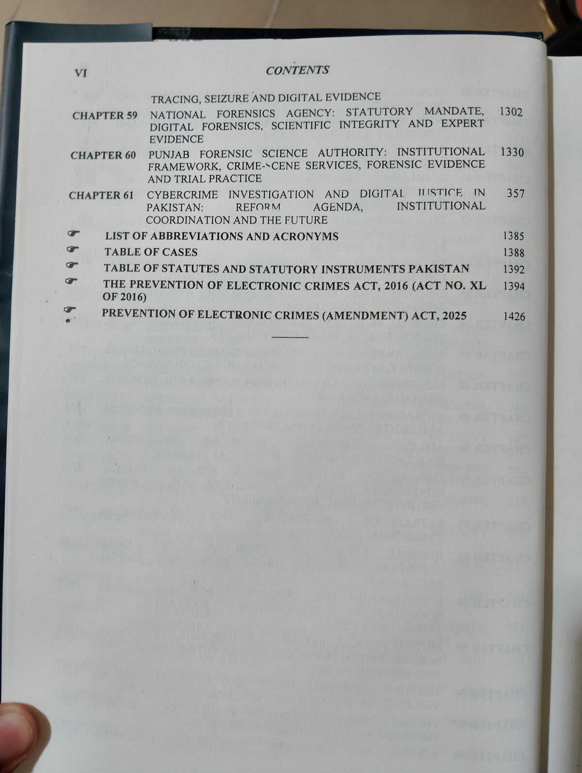 A close-up of an open book showing the contents page, with printed text listing chapters, abbreviations, table of cases, and statutes. A finger is visible holding the book open at the lower left edge.